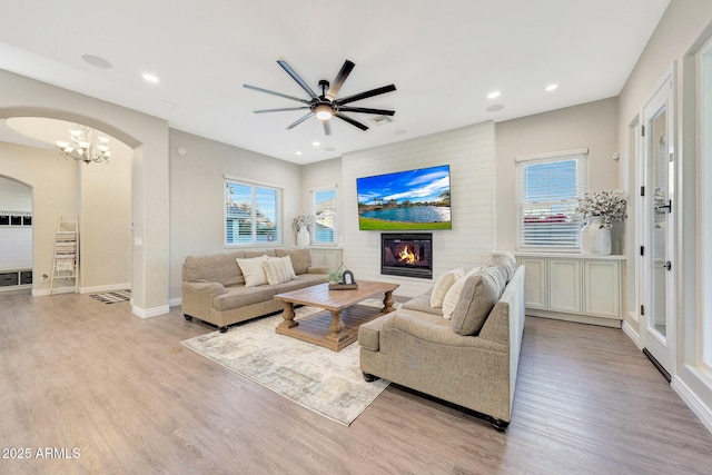 living room with a fireplace, ceiling fan, and light wood-type flooring