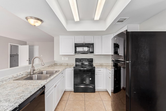 kitchen featuring a tray ceiling, sink, black appliances, light tile patterned floors, and white cabinetry