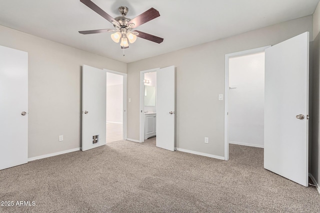 unfurnished bedroom with ceiling fan, ensuite bathroom, a spacious closet, and light carpet