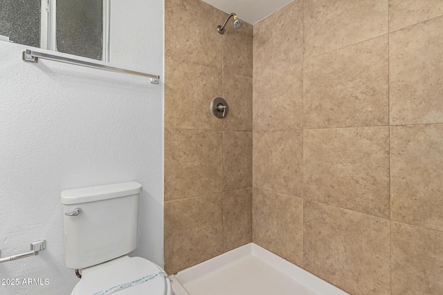 bathroom featuring toilet and a tile shower