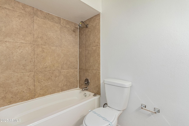 bathroom with tiled shower / bath combo and toilet