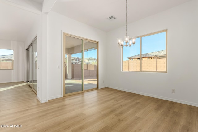 unfurnished dining area with light hardwood / wood-style floors, an inviting chandelier, and a healthy amount of sunlight