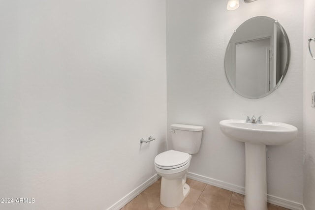 bathroom with toilet, sink, and tile patterned flooring