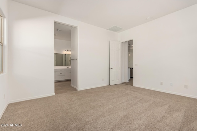 unfurnished bedroom featuring light colored carpet and connected bathroom