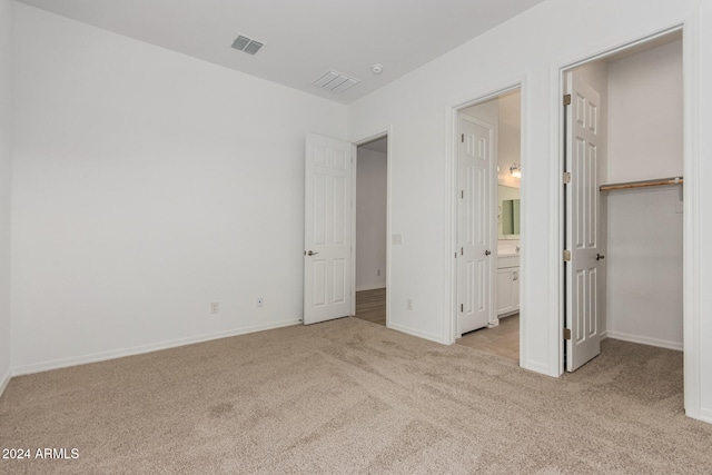 unfurnished bedroom featuring a closet, light carpet, and ensuite bathroom