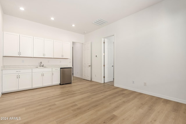 kitchen with light hardwood / wood-style floors, sink, stainless steel dishwasher, and white cabinets