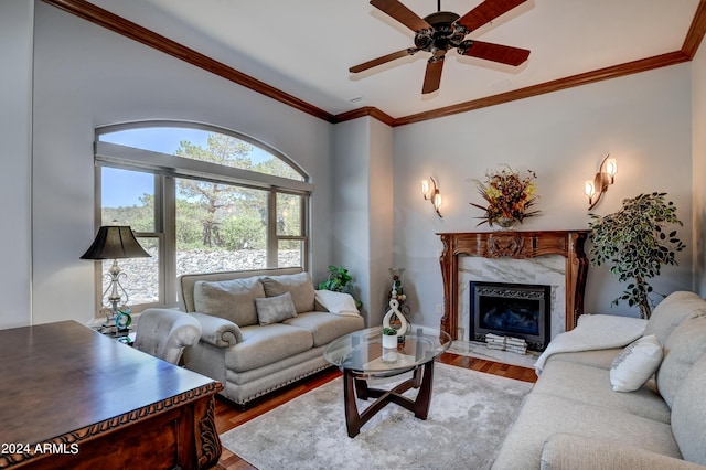 living room with ceiling fan, a fireplace, crown molding, and wood-type flooring
