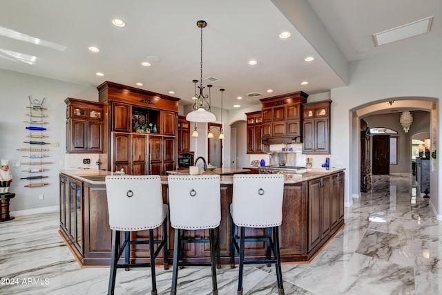 kitchen featuring a kitchen breakfast bar, decorative light fixtures, light stone counters, light tile patterned floors, and a large island with sink