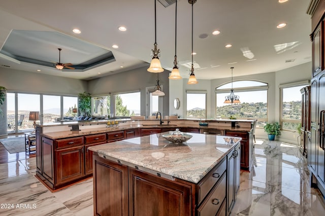 kitchen featuring decorative light fixtures, kitchen peninsula, light stone countertops, and a kitchen island