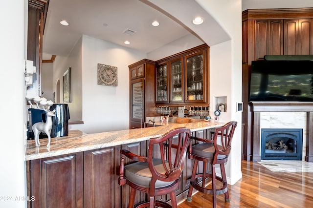 bar with light wood-type flooring and light stone countertops