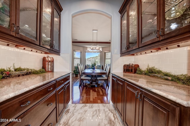 interior space with tasteful backsplash, light hardwood / wood-style flooring, light stone countertops, and hanging light fixtures