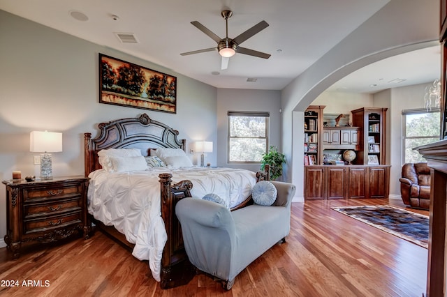 bedroom featuring ceiling fan, hardwood / wood-style flooring, and multiple windows
