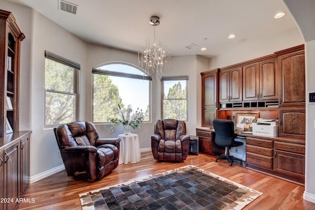 office with a wealth of natural light, an inviting chandelier, and light hardwood / wood-style flooring