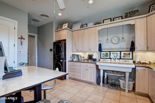 kitchen with light brown cabinets, stacked washer / dryer, ceiling fan, light tile patterned flooring, and hanging light fixtures
