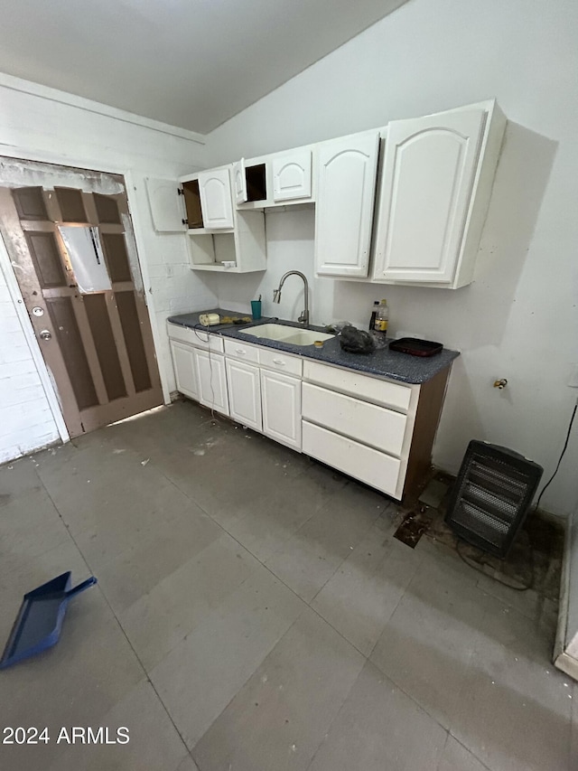 kitchen with white cabinets, vaulted ceiling, and sink