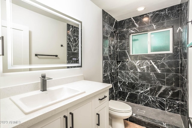 bathroom featuring vanity, toilet, and a tile shower