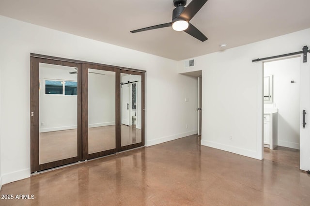 unfurnished room featuring a barn door, concrete floors, ceiling fan, and french doors