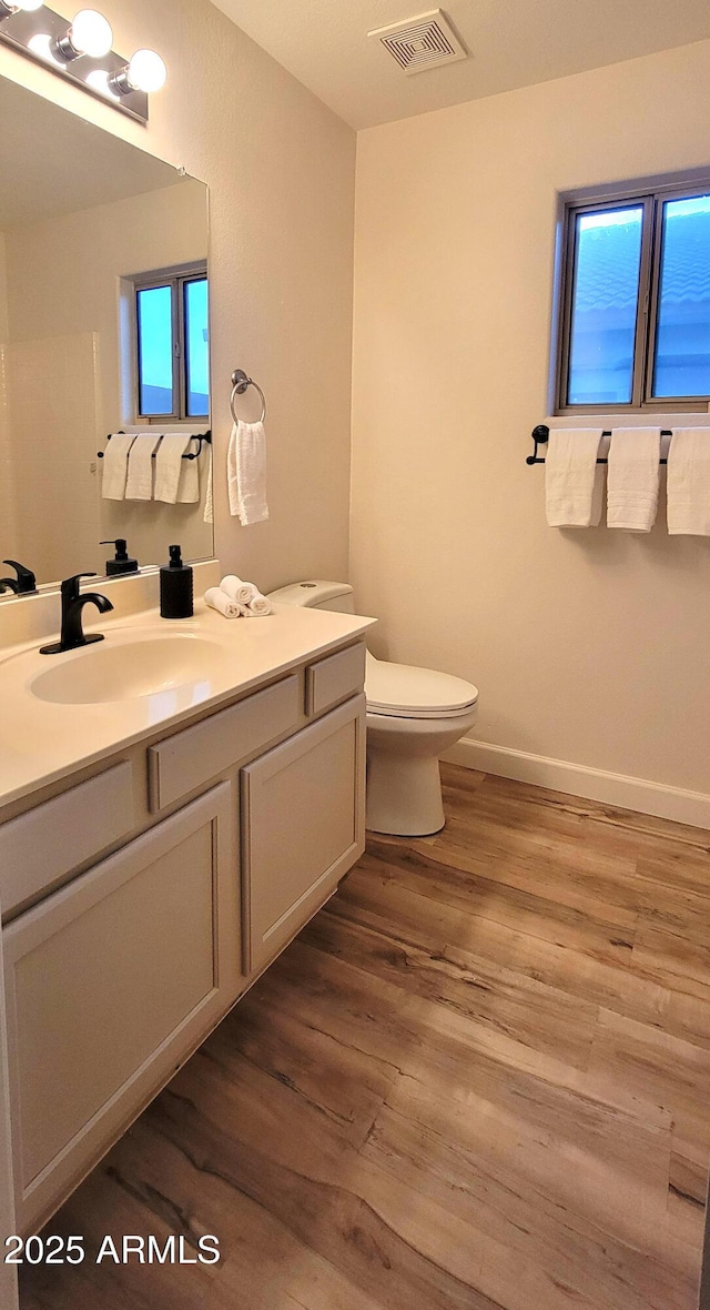 bathroom featuring wood-type flooring, toilet, and vanity