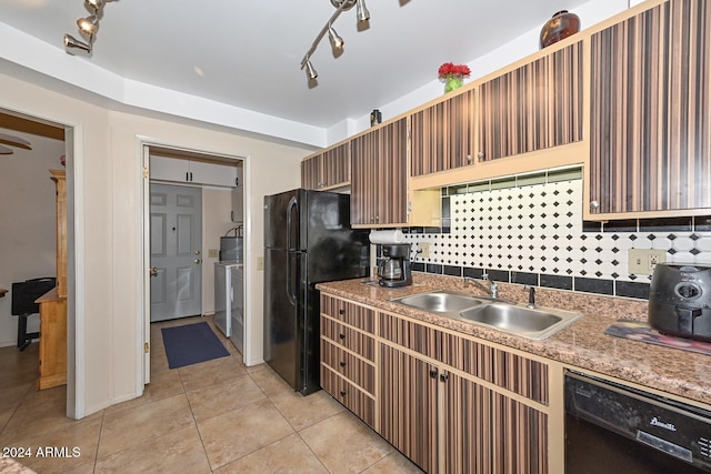 kitchen featuring rail lighting, tasteful backsplash, sink, washer and dryer, and black appliances