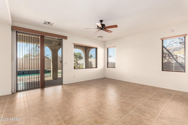 unfurnished room with ceiling fan, a wealth of natural light, and light tile patterned flooring