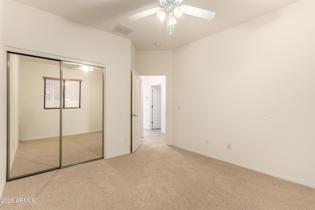 unfurnished bedroom with ceiling fan, a closet, and light carpet