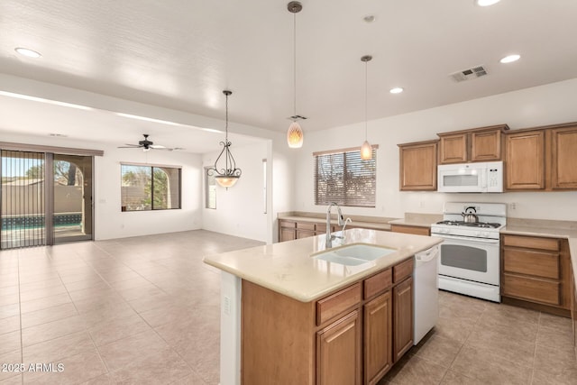 kitchen featuring ceiling fan, pendant lighting, sink, white appliances, and a kitchen island with sink