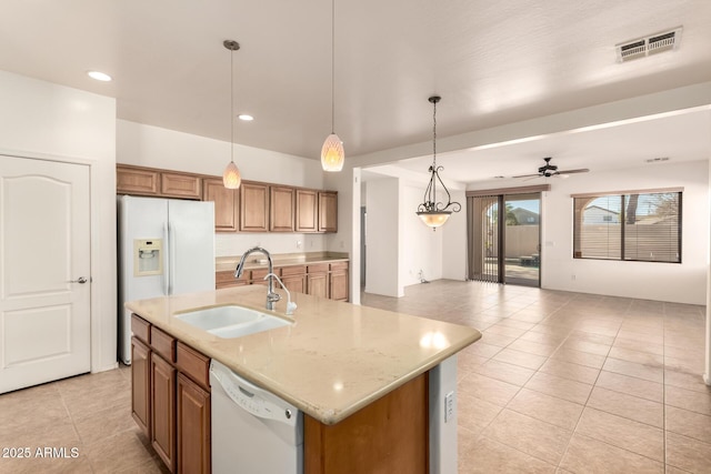 kitchen with decorative light fixtures, ceiling fan, a center island with sink, sink, and white appliances