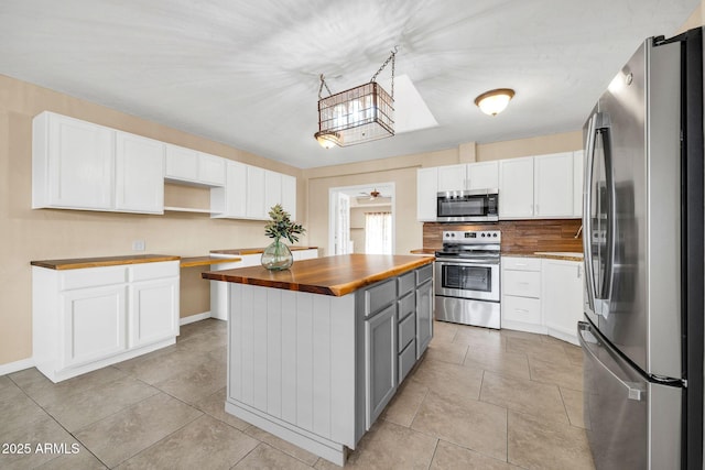 kitchen with gray cabinets, a kitchen island, butcher block countertops, white cabinetry, and stainless steel appliances