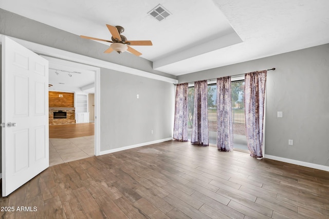 spare room featuring hardwood / wood-style flooring, ceiling fan, and a stone fireplace