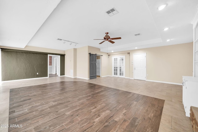 unfurnished living room featuring a barn door, track lighting, and ceiling fan