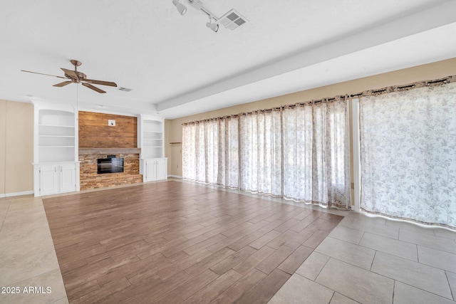 unfurnished living room featuring track lighting, ceiling fan, and built in shelves