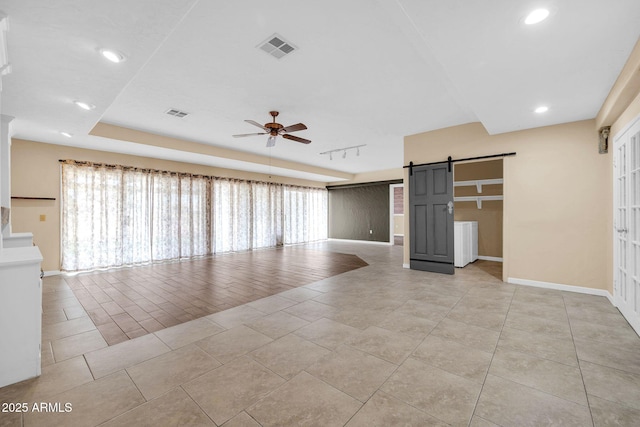 unfurnished living room featuring a wealth of natural light, a barn door, ceiling fan, and light tile patterned flooring