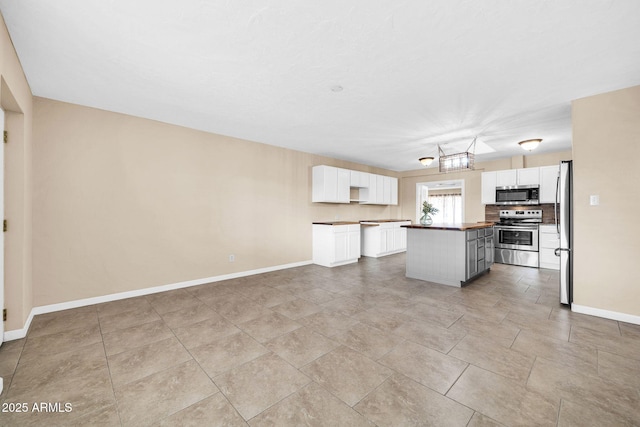 kitchen with white cabinetry, backsplash, a kitchen island, and appliances with stainless steel finishes