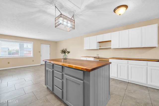 kitchen with gray cabinets, a kitchen island, white cabinetry, wooden counters, and light tile patterned floors