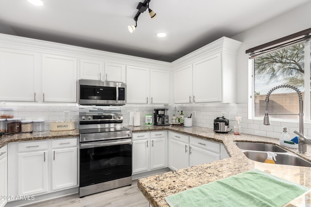 kitchen with stainless steel appliances, white cabinetry, sink, and tasteful backsplash