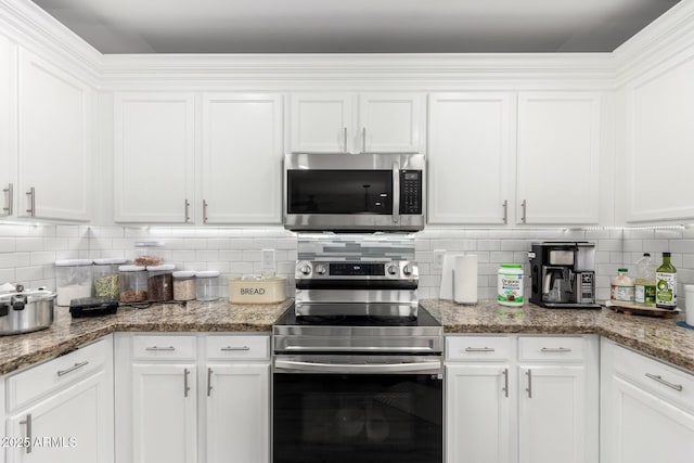 kitchen featuring white cabinetry, stainless steel appliances, backsplash, and dark stone countertops