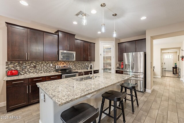 5012 S Girard St, Gilbert, AZ 85298 - kitchen featuring a kitchen breakfast bar, appliances with stainless steel finishes, a sink, wood tiled floor, and backsplash