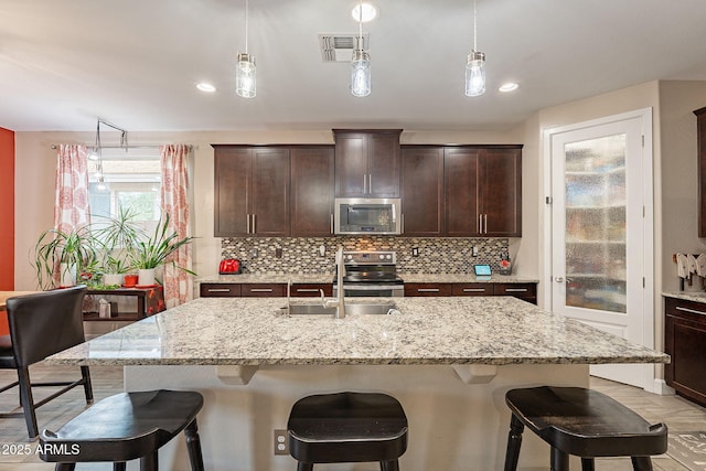 5012 S Girard St, Gilbert, AZ 85298 - kitchen with appliances with stainless steel finishes, visible vents, a kitchen bar, decorative backsplash, and a sink