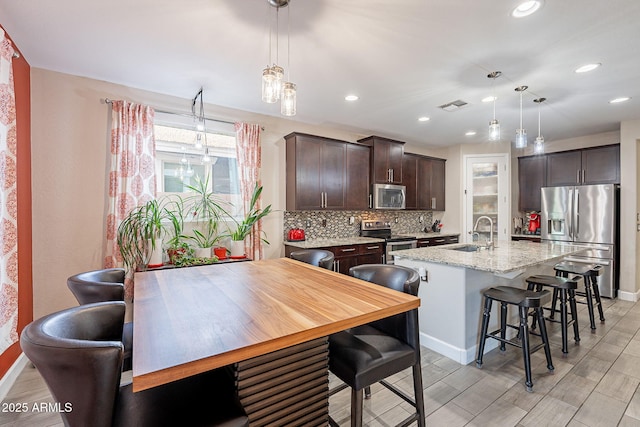 5012 S Girard St, Gilbert, AZ 85298 - kitchen featuring dark brown cabinetry, a center island with sink, decorative backsplash, stainless steel appliances, and a sink