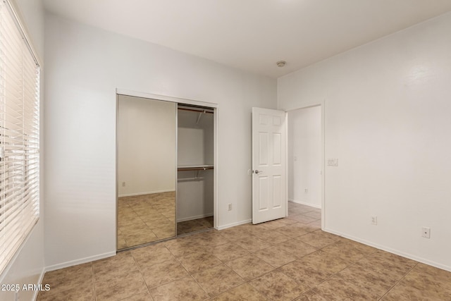 unfurnished bedroom with multiple windows, light tile patterned flooring, and a closet