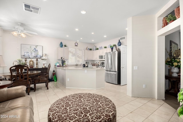kitchen with visible vents, a ceiling fan, a peninsula, and freestanding refrigerator