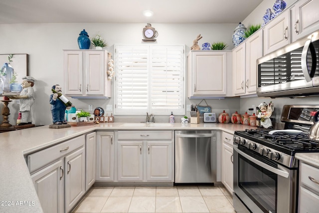kitchen with a sink, white cabinets, stainless steel appliances, and light countertops