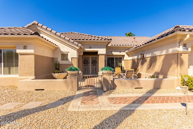 back of house featuring stucco siding, a fenced front yard, a tiled roof, and a gate
