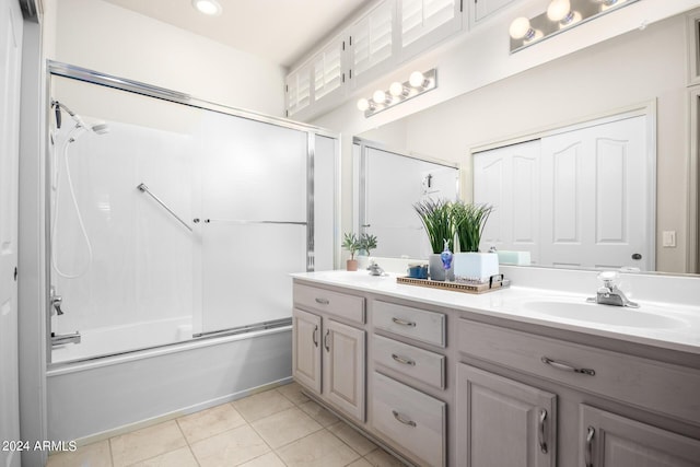 bathroom with double vanity, tile patterned flooring, shower / bath combination with glass door, and a sink
