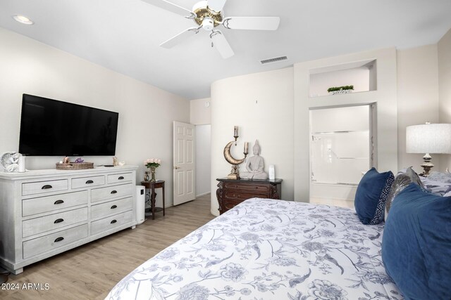bedroom with visible vents, connected bathroom, a ceiling fan, and light wood-style flooring