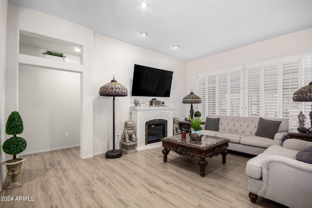 living room featuring a glass covered fireplace, recessed lighting, wood finished floors, and baseboards