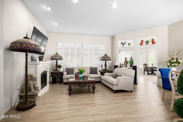 living area with recessed lighting, wood finished floors, a ceiling fan, and a glass covered fireplace