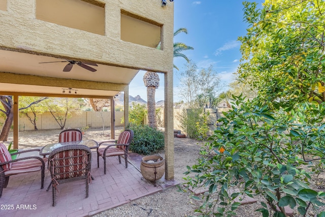 view of patio / terrace with a ceiling fan, a fenced backyard, and a mountain view