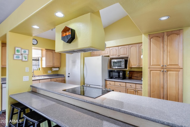 kitchen featuring black appliances, lofted ceiling, light brown cabinets, sink, and a breakfast bar