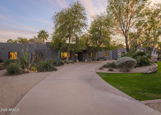 view of front facade with driveway, a lawn, and stucco siding